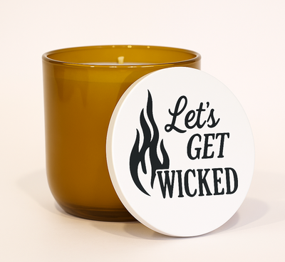 "Amber frosted glass candle with engraved ‘Let’s Get Wicked’ wooden lid, clean-burning wax, and cotton wick — a playful Halloween-inspired home accent.